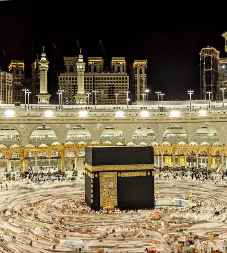 Vibrant night view of the Kaaba in Mecca, capturing Islamic architecture and worshippers.